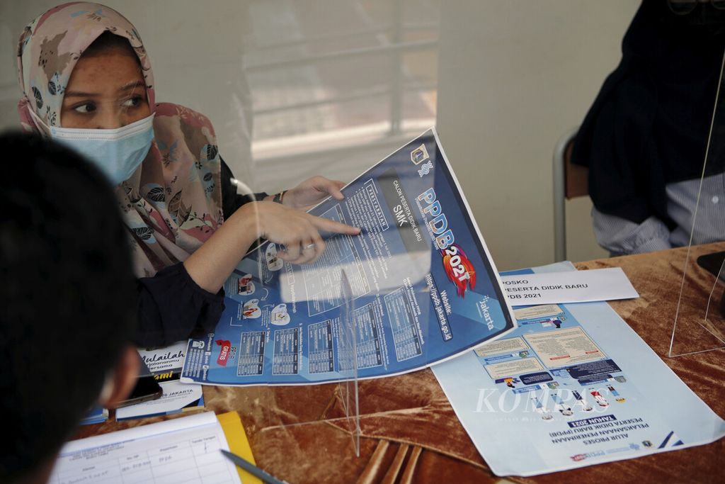 Guru menjelaskan kepada wali murid di posko pelaksanaan penerimaan peserta didik baru (PPDB) di SMK Negeri 70 Jakarta, Senin (7/6/2021).  