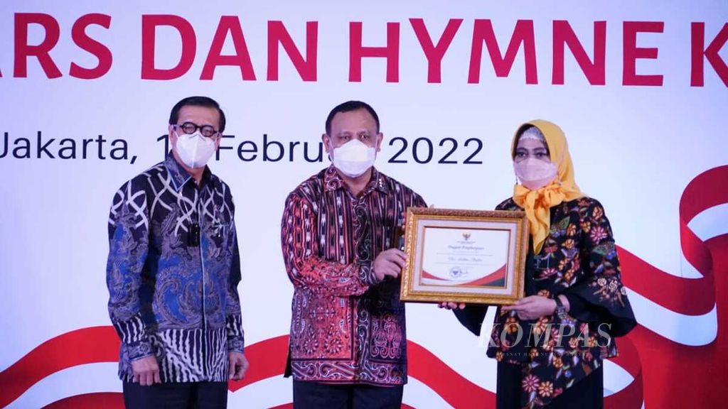 Ketua KPK Firli Bahuri menyerahkan piagam penghargaan kepada istrinya, yang juga merupakan pencipta lagu mars dan himne KPK, Ardina Safitri, di Gedung KPK, Jakarta, Kamis (17/2/2022). Menteri Hukum dan HAM Yasonna Laoly turut menyaksikan.