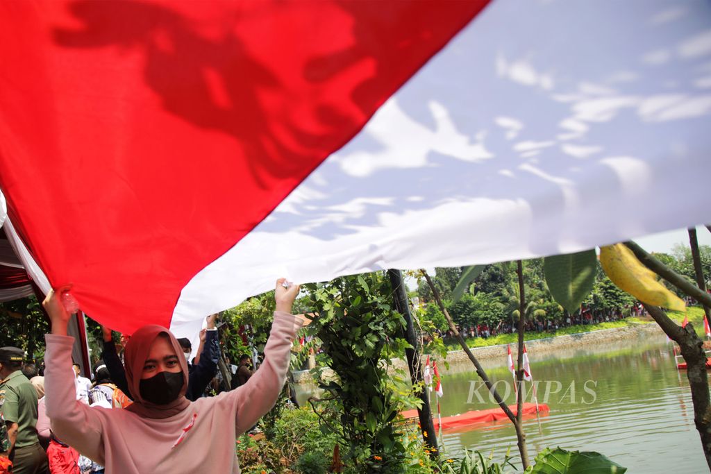 Warga ikut membentangkan bendera Merah Putih sepanjang 3.522 meter mengelilingi Setu Parigi, Tangerang Selatan, Banten dalam acara Pondok Aren Berkibar, Kamis (18/8/2022). Kegiatan ini digelar untuk memeriahkan HUT Ke-77 Kemerdekaan Indonesia. 