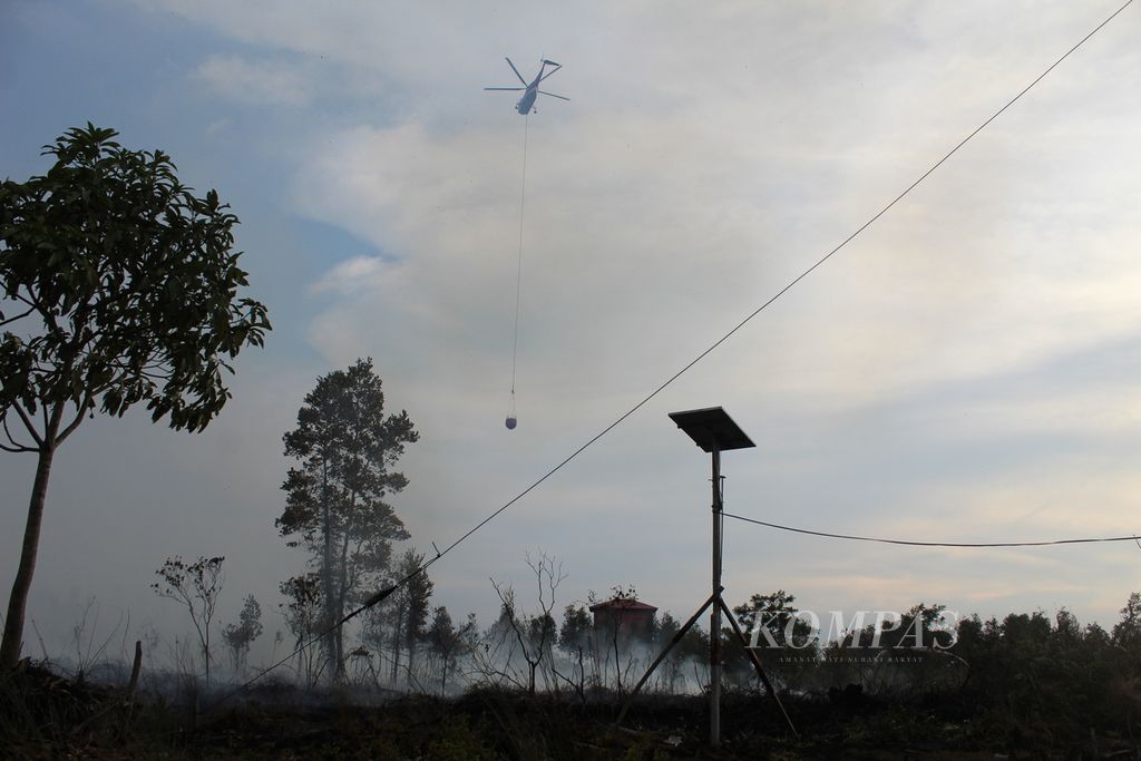 Petugas pemadam kebakaran berupaya memadamkan api yang membakar lahan gambut di Desa Tumbang Nusa, Kabupaten Pulang Pisau, Kalimantan Tengah, Kamis (22/9/2023). Pengerahan helikopter<i> waterbombing </i>pun dilakukan. 