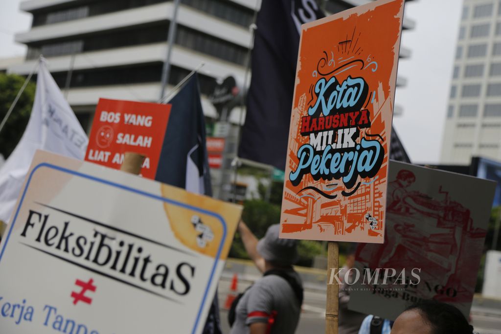 Buruh mengangkat poster saat menggelar aksi damai merayakan hari buruh internasional atau May Day di kawasan Patung Kuda, Jalan MH Thamrin, Jakarta, Senin (1/5/2023). Dalam aksinya, mereka, antara lain, menuntut pencabutan UU Cipta Kerja dan disahkannya RUU Perlindungan Pekerja Rumah Tangga.