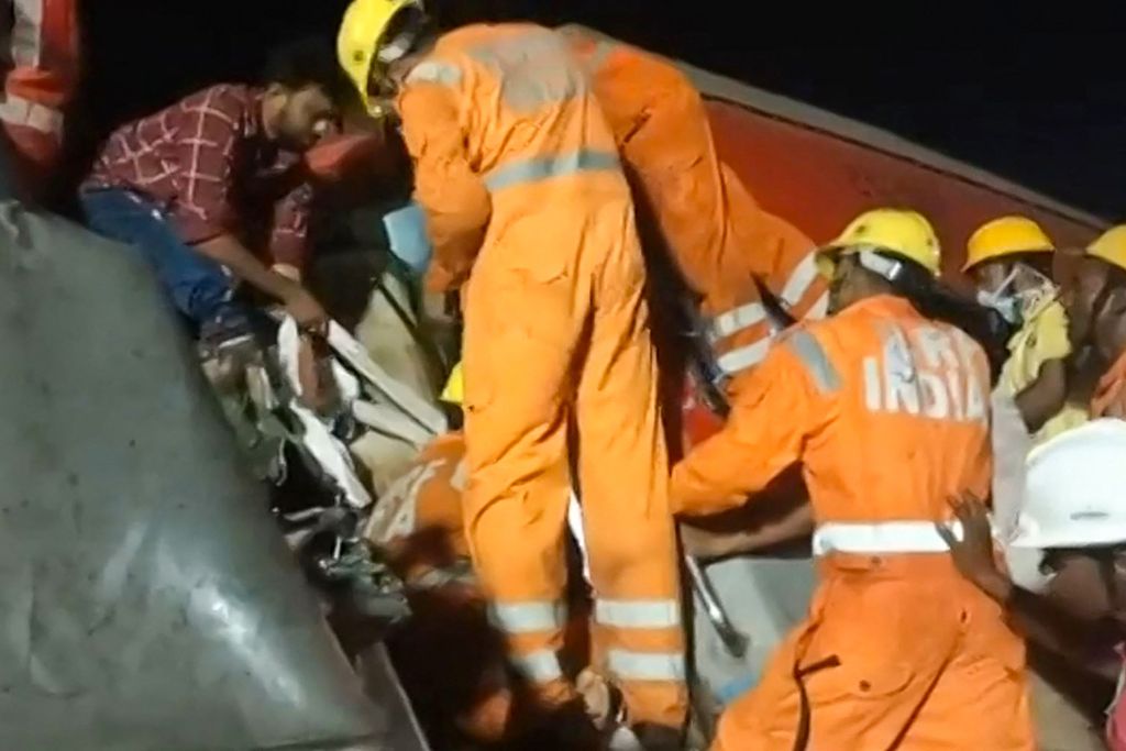 Para petugas penyelamat mencoba meraih korban yang terjebak dalam gerbong akibat kecelakaan kereta di dekat Balasore, sekitar 200 kilometer dari Bhubaneswar, ibu kota Negara Bagian Odisha, India, 2 Juni 2023. Lebih dari 200 orang tewas dan 900 orang terluka dalam kecelakaan tersebut. 