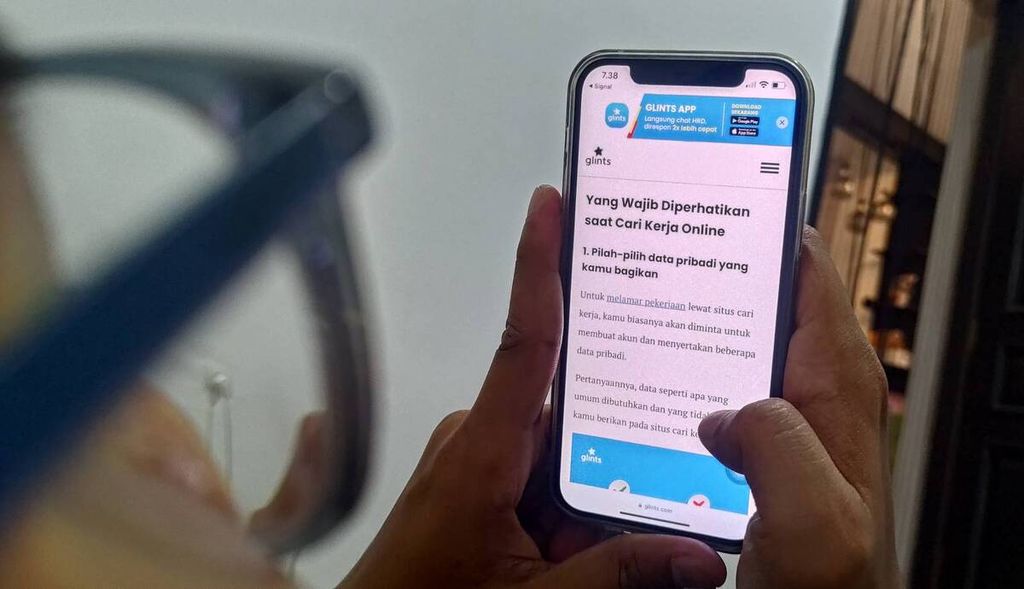 Seorang laki-laki melihat panduan pencarian lowongan kerja yang disediakan platform Glints, Rabu (21/8/2024).