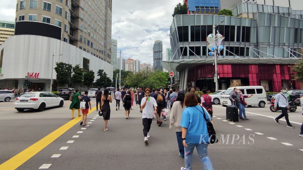 Para pejalan kaki menyeberang jalan di kawasan Orchard Road, yang kerap menjadi salah satu tujuan wisata di Singapura, Jumat (4/11/2022). 