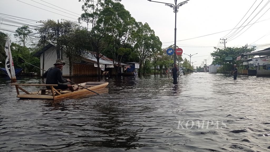 Warga di Kotawaringin Barat, Kalimantan Tengah, melintas dengan perahu kayu di tengah banjir, Selasa (1/10/2022).