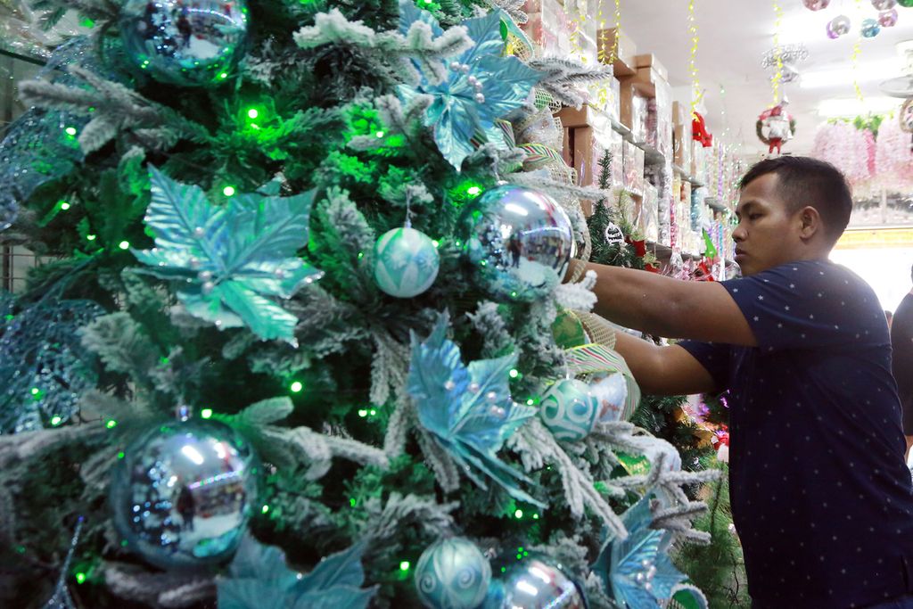 Salah seorang pekerja menyiapkan pohon Natal untuk dijual di salah satu toko di Pasar Asemka, Jakarta Barat, Senin (12/12/2022).