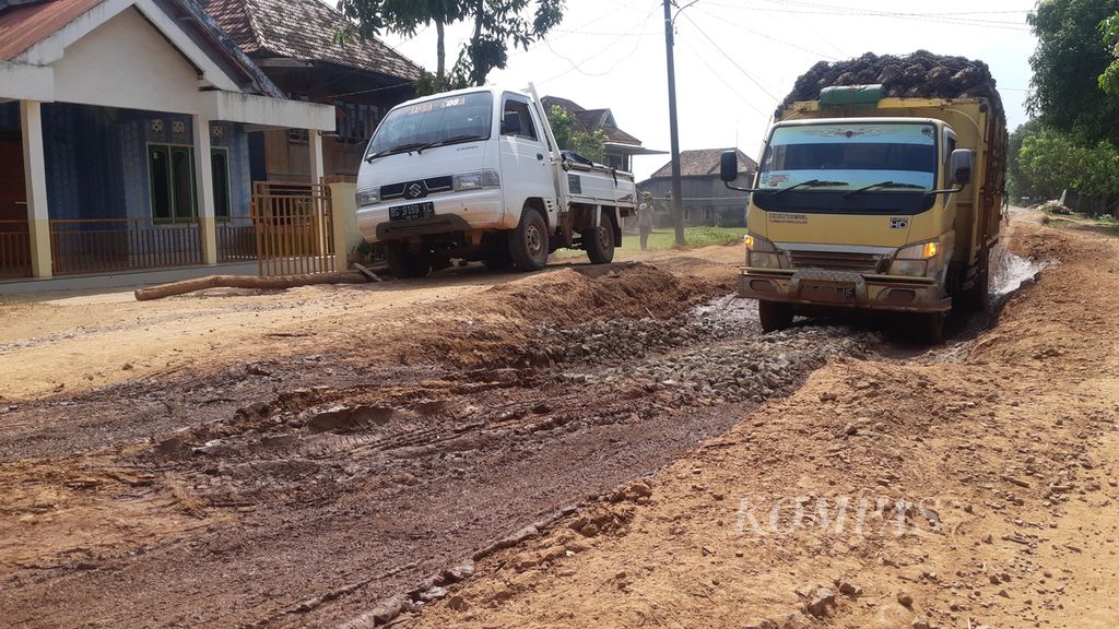 Dua kendaraan pengangkut komoditas melewati jalan rusak di Desa Sukadamai, Kecamatan Pangkalan Lampam, Kabupaten Ogan Komering Ilir, Sumatera Selatan, Selasa (23/5/2023). 