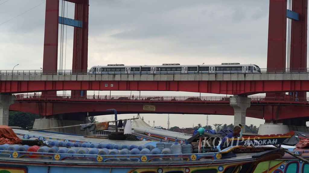 LRT Palembang melintas di sekitar dermaga kapal Pasar 16 Ilir berlatar Jembatan Ampera di Kota Palembang, Sumatera Selatan, Sabtu (25/4/2023). Lintas pelayanan LRT dimulai dari Stasiun Bandara Internasional Sultan Mahmud Badaruddin II hingga Jakabaring Sport City. 