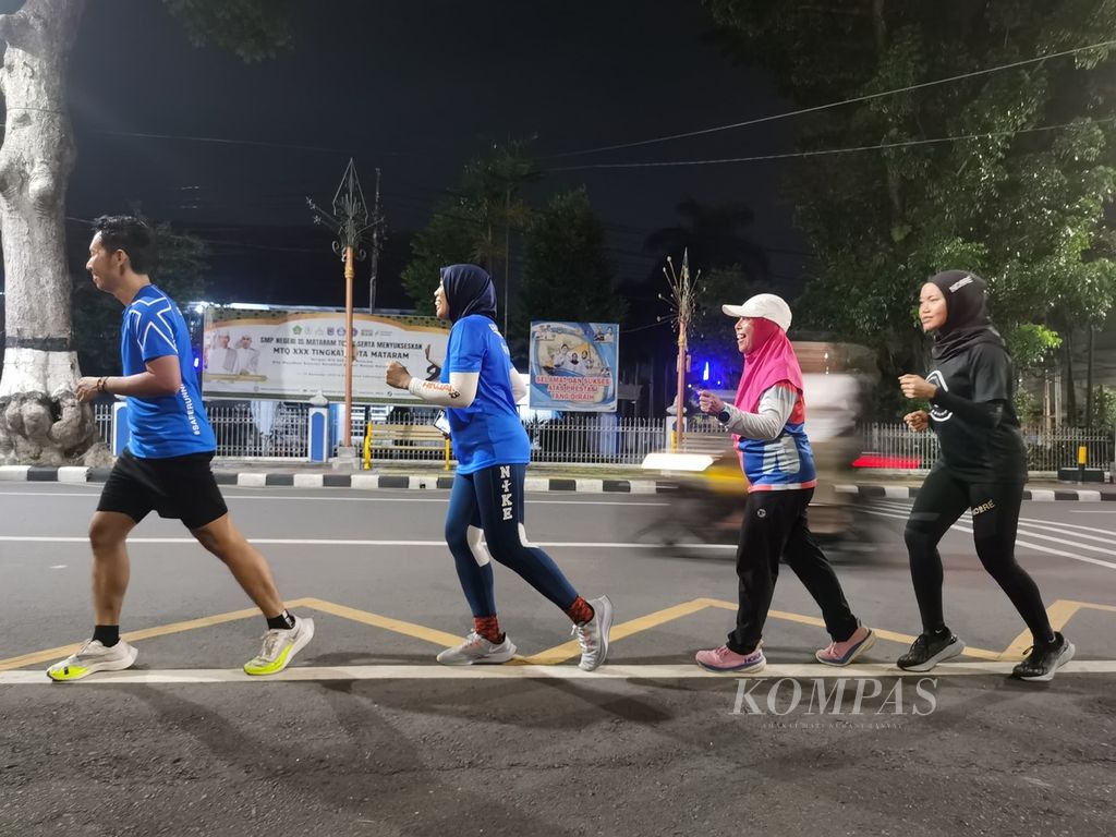 Rombongan pelari yang tergabung dalam komunitas Runjani melintasi Jalan Pejanggik, Kota Mataram, Nusa Tenggara Barat, Rabu (3/1/2024) malam.