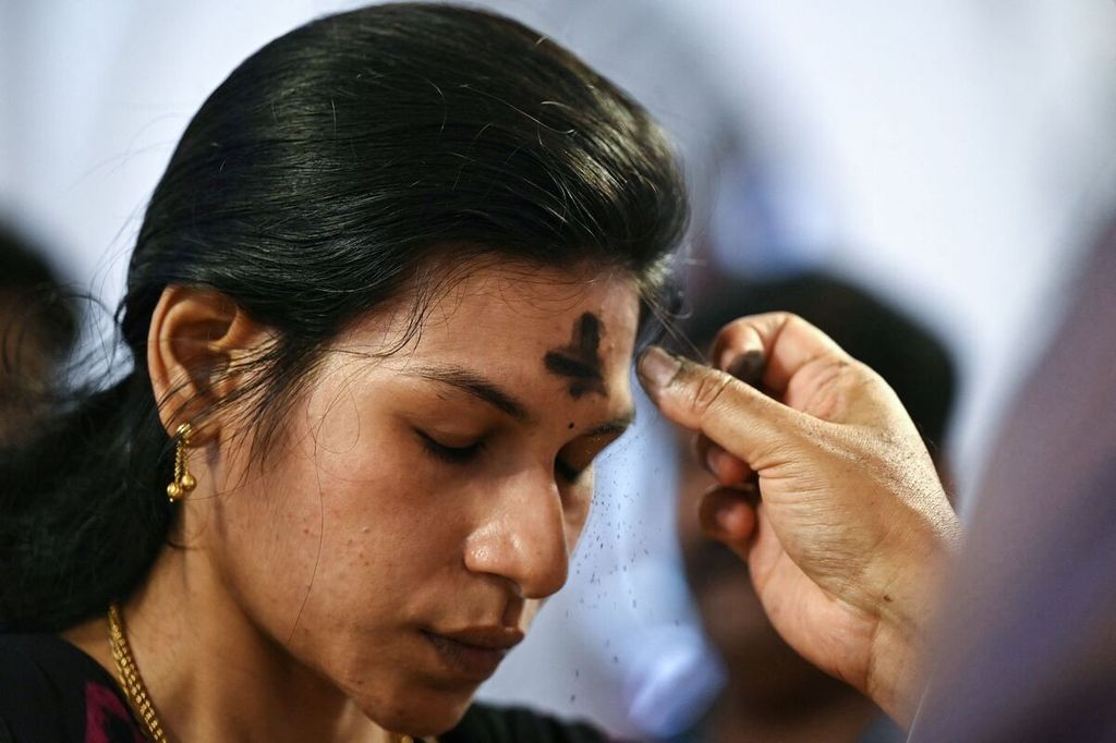 Seorang pastor menorehkan tanda salib di dahi seorang umat dalam perayaan Rabu Abu di Katedral Basilica St Thomas, Chennai, India, Rabu (14/2/2024).  