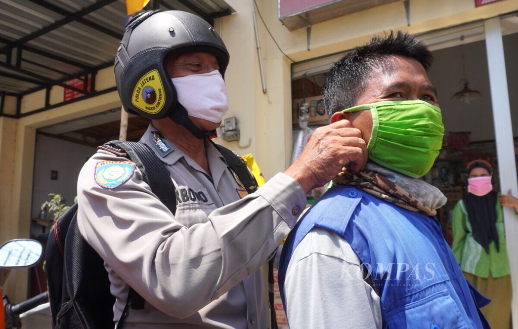 Polisi membantu masyarakat memakai masker di Pasar Kejambon, Kecamatan Tegal Timur, Kota Tegal, Jawa Tengah (10/9/2020). Selain memberi masker, polisi bersama dengan TNI dan Pemerintah Kota Tegal menyosialisasikan penerapan sanksi denda bagi pelanggar protokol kesehatan.