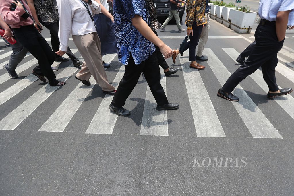Pejalan kaki menyeberang di Jalan MH Thamrin, Jakarta, Senin (9/10/2023). Fenomena kulminasi Matahari atau fenomena ketika Matahari tepat berada di atas garis khatulistiwa. Fenomena ini sering diistilahkan sebagai hari tanpa bayangan.