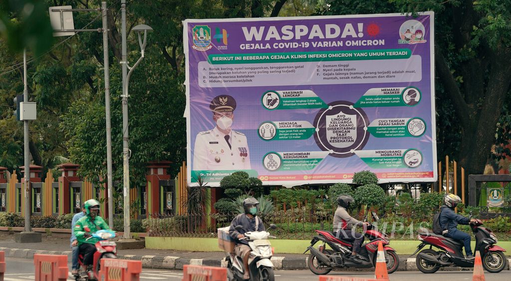 Warga melintasi baliho untuk waspada gejala Covid-19 varian Omicron di Balai Kota Bekasi, Jawa Barat, Kamis (10/2/2022). 