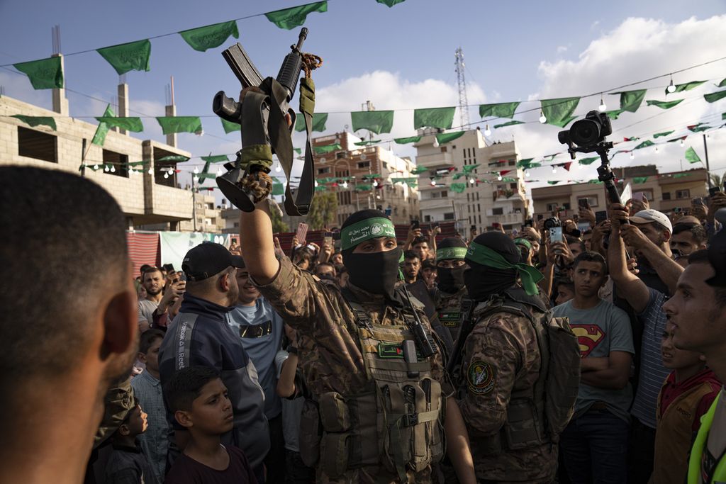  Seorang anggota sayap militer Hamas mengangkat senapan yang direbut dari pasukan keamanan Israel dalam parade di kamp pengungsi Nusseirat di Jalur Gaza tengah, 30 Juni 2023. 