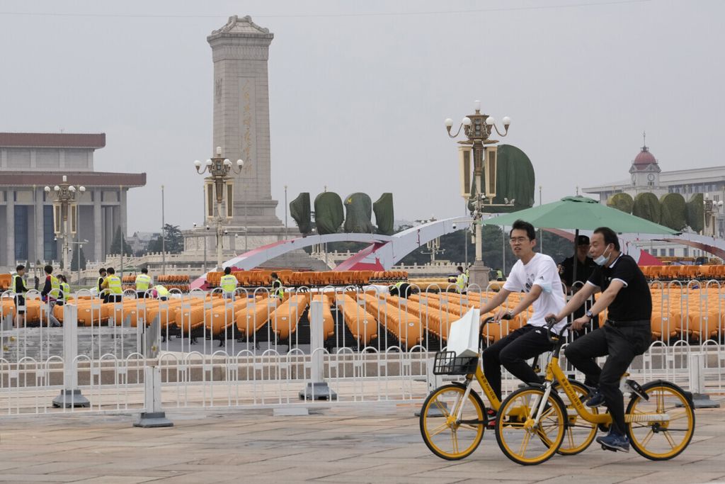 Warga berkendara melewati barisan kursi oranye yang ditata di Lapangan Tiananmen, Beijing, China, 23 Juni 2021. Lapangan Tiananmen ditutup bagi publik menjelang peringatan 100 tahun berdirinya Partai Komunis China. 
