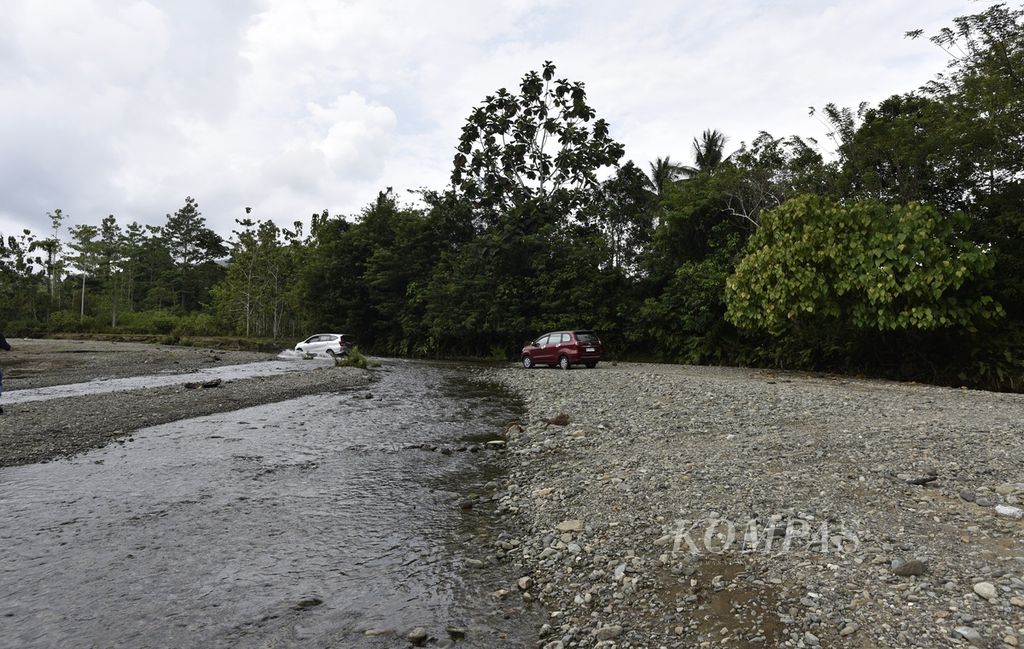 Mobil menyeberangi Sungai Buton untuk menuju ke areal pertanian di Desa Buton, Pulau Obi, Halmahera Selatan, Maluku Utara, Minggu (26/11/2023). Saat hujan tinggi dan air sungai penuh, kendaraan tidak dapat melintas karena belum ada jembatan di lokasi tersebut.