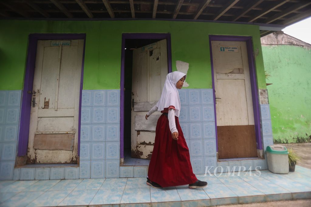 Seorang murid melintas di depan pintu WC yang rusak dan tidak kunjung diperbaiki di SDN Bulurejo 1, Kecamatan Mertoyudan, Kabupaten Magelang, Jawa Tengah, Rabu (10/5/2023). Sekolah itu saat ini menjadi tempat menimba ilmu bagi 61 murid. Jumlah murid yang sedikit membuat sekolah itu mengalami kesulitan dalam hal biaya operasional tahunan. 