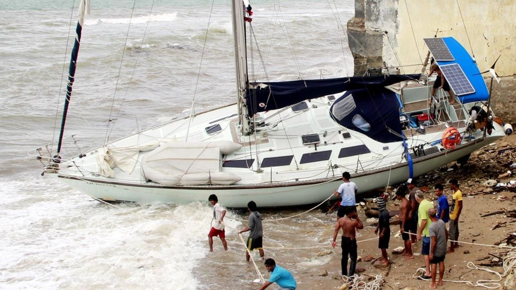 Sejumlah warga memasang tali di sebuah perahu layar (<i>yacht</i>) milik wisatawan asal Australia yang terdampar di Kupang, Nusa Tenggara Timur, Kamis (22/12). <i>Yacht </i>tersebut terdampar di Kupang akibat cuaca buruk yang melanda wilayah perairan NTT. 
