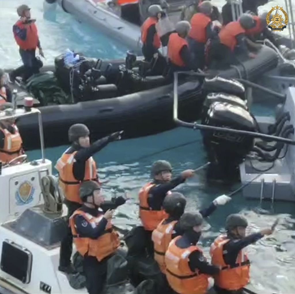 Awak kapal Penjaga Pantai China mengacungkan pisau dan parang saat berhadapan dengan kapal Angkatan Laut (AL) Filipina yang akan memasok logistik ke pos AL Filipina di kapal BRP Sierra Madre di Beting Thomas Kedua, Laut China Selatan, Senin (17/6/2024). 