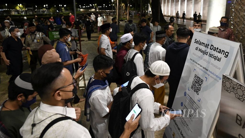 Jemaah memindai kode batang aplikasi Peduli Lindungi sebelum memasuki masjid untuk melaksanakan shalat Tarawih pertama Ramadhan 1443 Hijriah di Masjid Istiqlal, Jakarta, Sabtu (2/4/2022).  