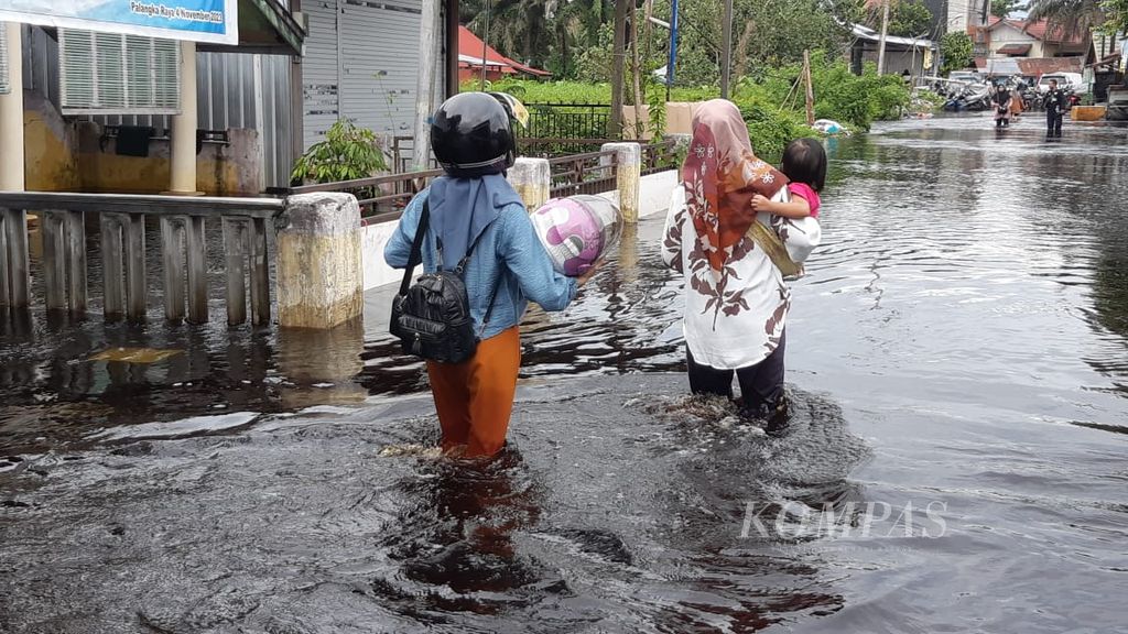 Warga Kelurahan Palangka, Kota Palangkaraya, Kalimantan Tengah melintas di tengah banjir di Jalan Arut, Kota Palangkaraya, pada Minggu (10/3/2024).