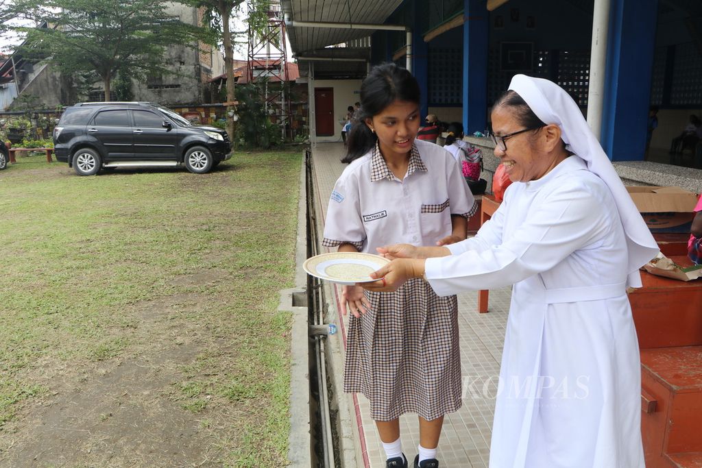 Siswi Sekolah Luar Biasa-B, Nathalie, memberi air cuci tangan kepada Ketua Yayasan Karya Murni Suster Desideria Saragih di Medan, Sumatera Utara, Rabu (30/8/2023). 