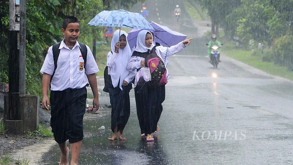 Pelajar menempuh perjalanan pulang sekolah saat hujan lebat di Desa Kaliagung, Sentolo, Kulon Progo, DI Yogyakarta, Senin (27/11/2017).