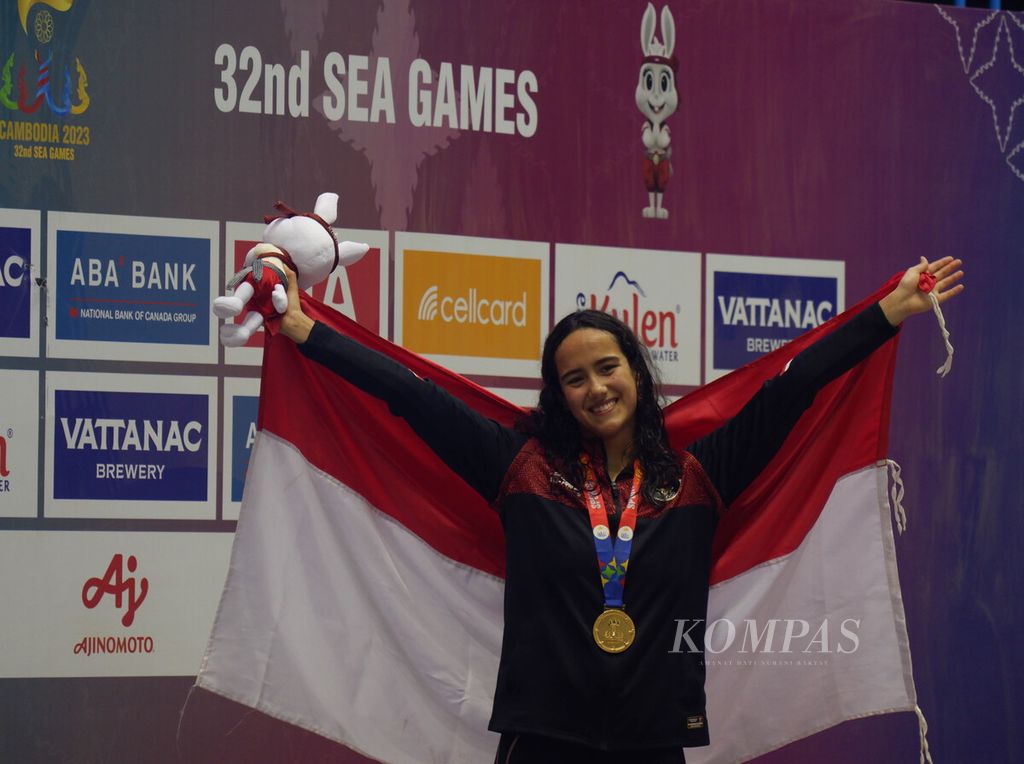 Perenang putri Indonesia, Masniari Wolf, berpose dengan medali emas usai menjuarai nomor 50 meter gaya punggung di Akuatik Center Kompleks Olahraga Morodok Techo, Minggu (7/5/2023) malam.