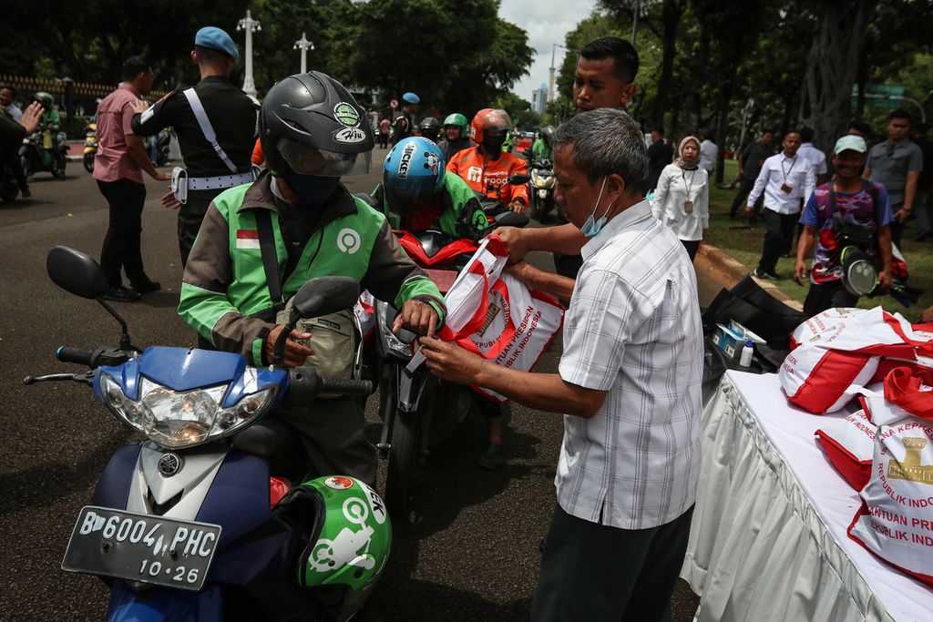 Seorang pengemudi ojek daring mencelupkan jari ke tinta sebagai tanda telah menerima paket sembako di depan Istana Merdeka, Jakarta, Kamis (13/4/2023). 