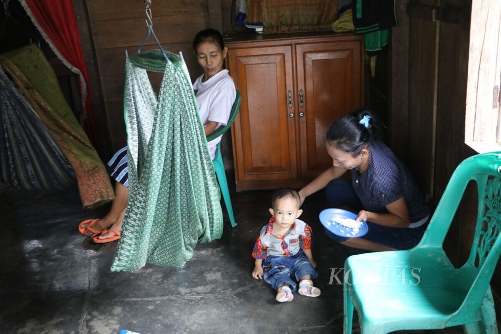 Arnis Gulo (21), petani karet, memberikan nasi tanpa lauk kepada anaknya yang baru berusia satu tahun di Desa Lakhene, Kecamatan Mandrehe, Kabupaten Nias Barat, Sumatera Utara, Minggu (13/1/2019). 