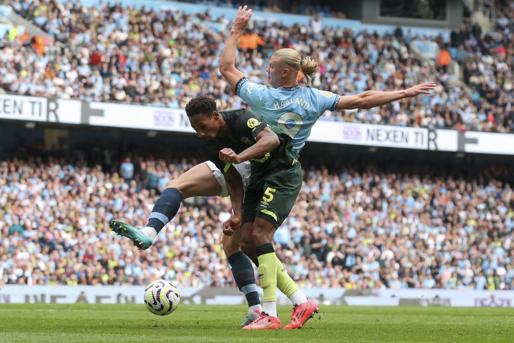 Pemain Brentford, Ethan Pinnock (depan), berduel dengan striker Manchester City, Erling Haaland, pada laga Liga Inggris di Manchester, Sabtu (14/9/2024). City menang dengan skor 2-1. 