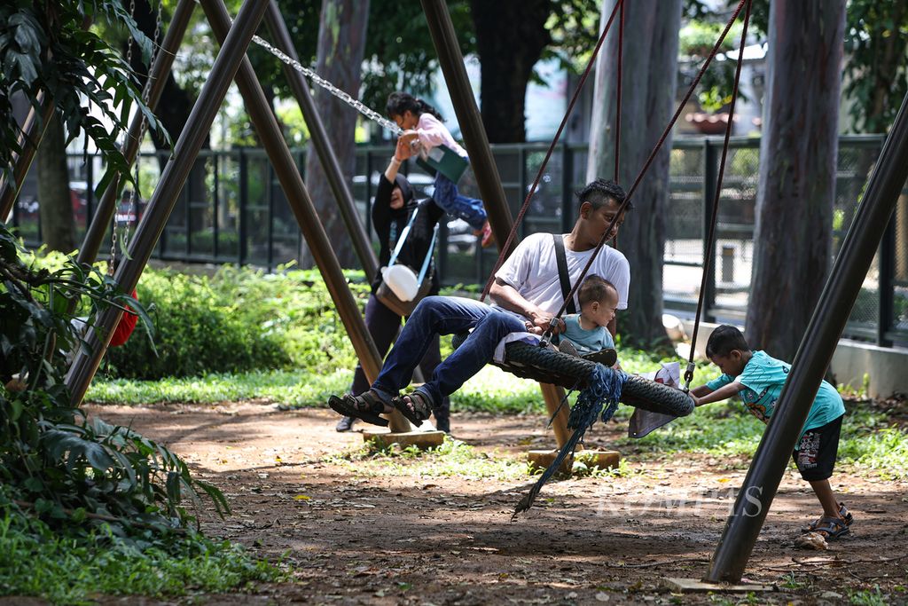 Orangtua mendampingi anak-anaknya bermain ayunan di Tebet Eco Park, Jakarta Selatan, Jumat (12/4/2024). 