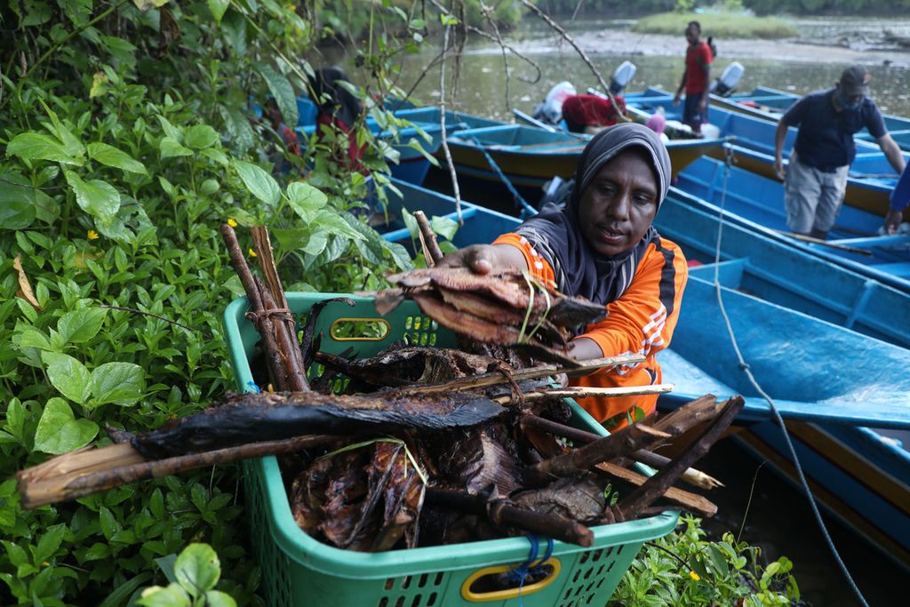 Warga menurunkan ikan asap dari perahu untuk dijual di Pasar Mambunibuni di Distrik Kokas, Kabupaten Fakfak, Papua Barat, Sabtu (19/6/2021)