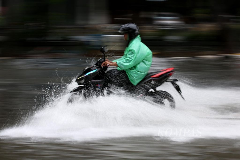 Ilustrasi. Warga dengan mengendarai motor berusaha melalui genangan banjir di kawasan Kelapa Gading, Jakarta Utara, Jumat (22/3/2024). 