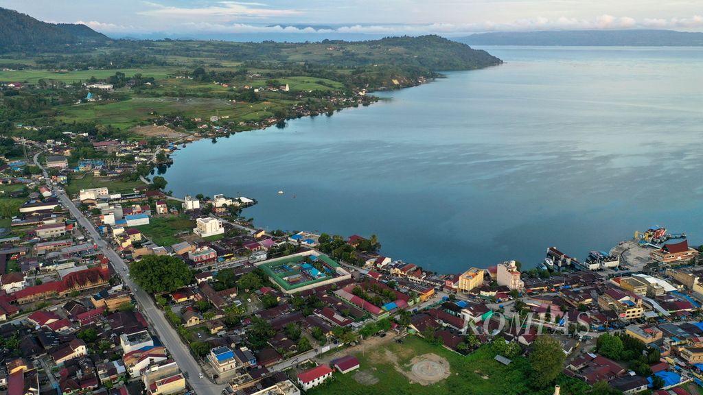 Foto udara Kota Balige di pinggiran Danau Toba di Kabupaten Toba, Sumatera Utara, Jumat (8/12/2023). Kota Balige terus berbenah menyambut wisatawan. Danau Toba telah ditetapkan menjadi salah satu dari lima destinasi wisata superprioritas oleh Kementerian Pariwisata dan Ekonomi Kreatif. KOMPAS/AGUS SUSANTO (AGS) 8-12-2023