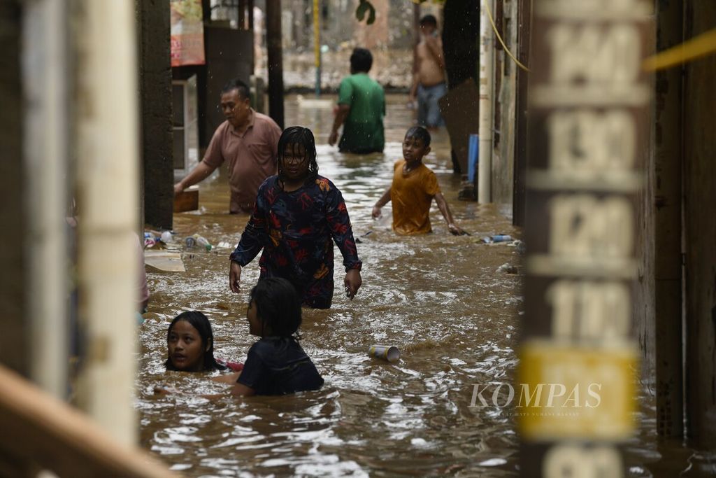 Anak-anak bermain banjir di kawasan Rawajati, Pancoran, Jakarta Selatan, Selasa (9/2/2021). Banjir akibat luapan Sungai Ciliwung yang merendam permukiman warga di tiga RW di Kelurahan Rawajati tersebut berangsur surut. 