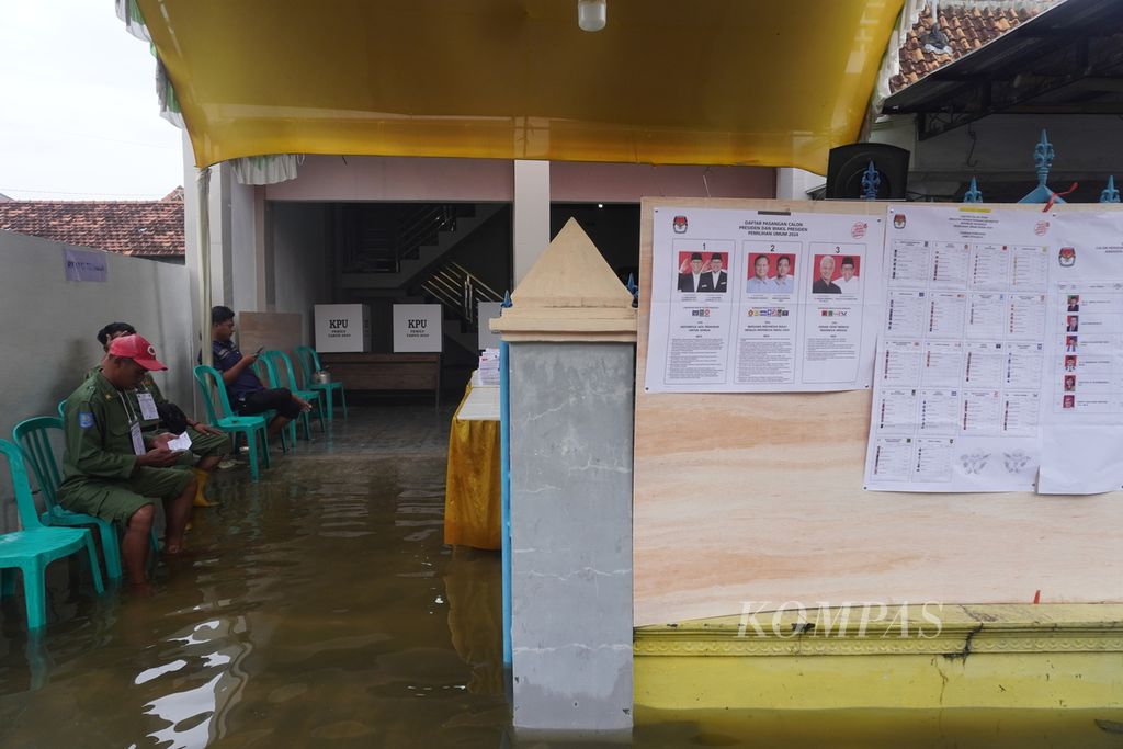 Petugas menunggu para pemilih di TPS 02 Desa Ngelowetan, Kecamatan Mijen, Kabupaten Demak, Jawa Tengah, Rabu (14/2/2024), yang sedang dilanda banjir.