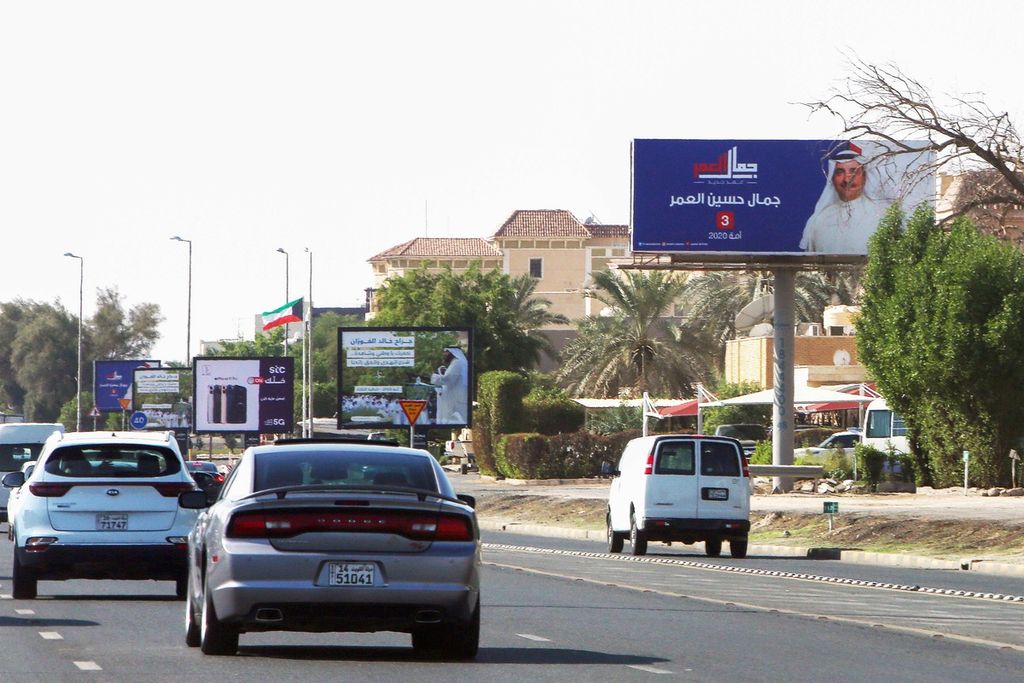 Kendaraan melaju di salah satu ruas jalan di Kuwait City, Kuwait, 22 November 2020, sementara papan reklame yang menampilkan calon anggota legislatif terpajang di tepi jalan. 
