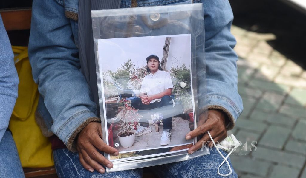 Rini Hanifah (43) memegang foto anaknya Agus Rainsyah yang menjadi korban dalam Tragedi Kanjuruhan dalam sidang perdana kasus Tragedi Kanjuruhan di Pengadilan Negeri Surabaya, Jawa Timur, Senin (16/1/2023). 