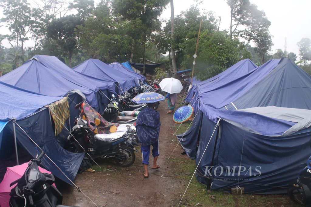 Sejumlah warga melintasi tenda-tenda pengungsian di Desa Cibulakan, Kecamatan Cugenang, Kabupaten Cianjur, Jawa Barat, Jumat (16/12/2022). Ratusan orang mengungsi di tempat tersebut setelah rumah mereka ambruk dilanda gempa, Senin (21/11) silam. 