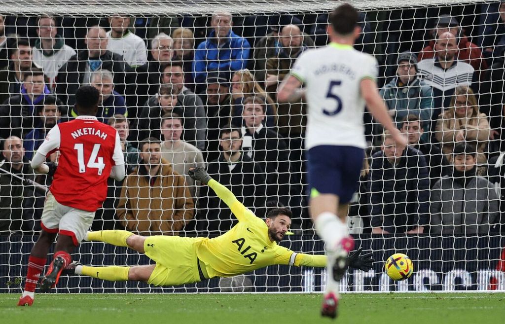 Kiper Tottenham Hotspur, Hugo Lloris, melompat untuk menghalau bola, tetapi gagal mencegah gawangnya dibobol pemain Arsenal, Martin Odegaard, pada laga Liga Inggris di Stadion Tottenham Hotspur, London, Minggu (15/1/2023). Pada laga itu, Arsenal menang 2-0. 
