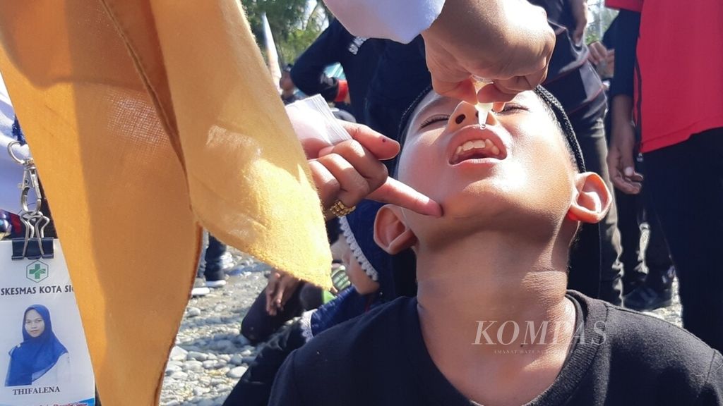 Para tenaga kesehatan meneteskan imunisasi polio kepada salah seorang anak sekolah dasar dalam subpekan imunisasi nasional di Kabupaten Pidie, Aceh, Senin (28/11/2022). Imunisasi massal dilakukan pasca penemuan empat kasus postif polio di kabupaten itu.