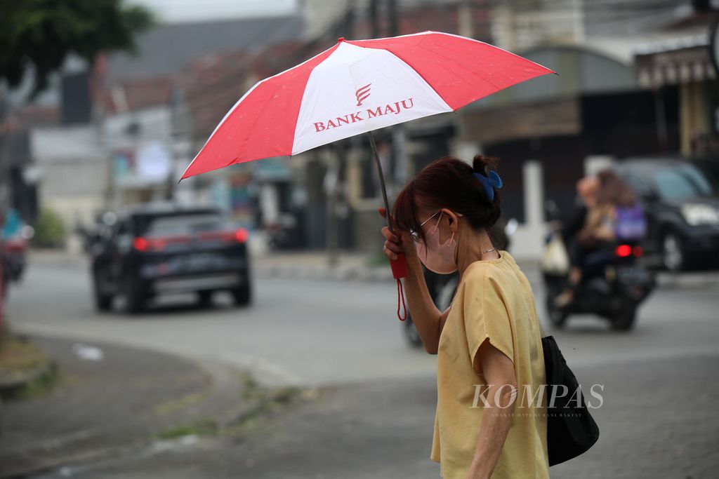 Warga menggunakan payung saat gerimis, tidak sampai turun hujan, di Jalan Sumatera, Serpong, Tangerang Selatan, Rabu (23/8/2023).