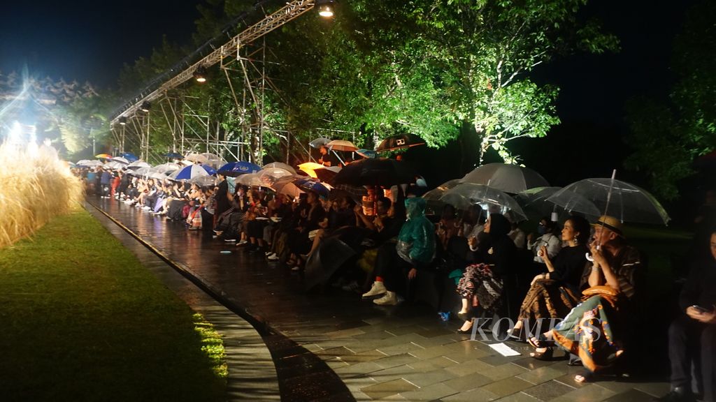 Para penikmat fashion bergeming dibawah hujan dengan payung dan jas hujan yang mengguyur kawasan Candi Borobudur di Magelang, Jawa Tengah pada Rabu malam (30/11/2022). Mereka menyaksikan peragaan busana "Edward Hutabarat Autumn Winter 2023" yang menampilkan busana dari kain tenun Sumba Barat.
