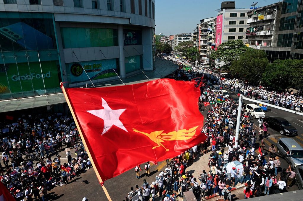 Bendera partai Liga Nasional untuk Demokrasi (NLD) berkibar di atas ribuan pengunjuk rasa yang kembali turun ke jalan menentang kudeta militer di Yangon, Myanmar, Rabu (10/2/2021). Penguasa militer Myanmar telah melarang aksi damai yang dilakukan oleh gerakan sipil. 