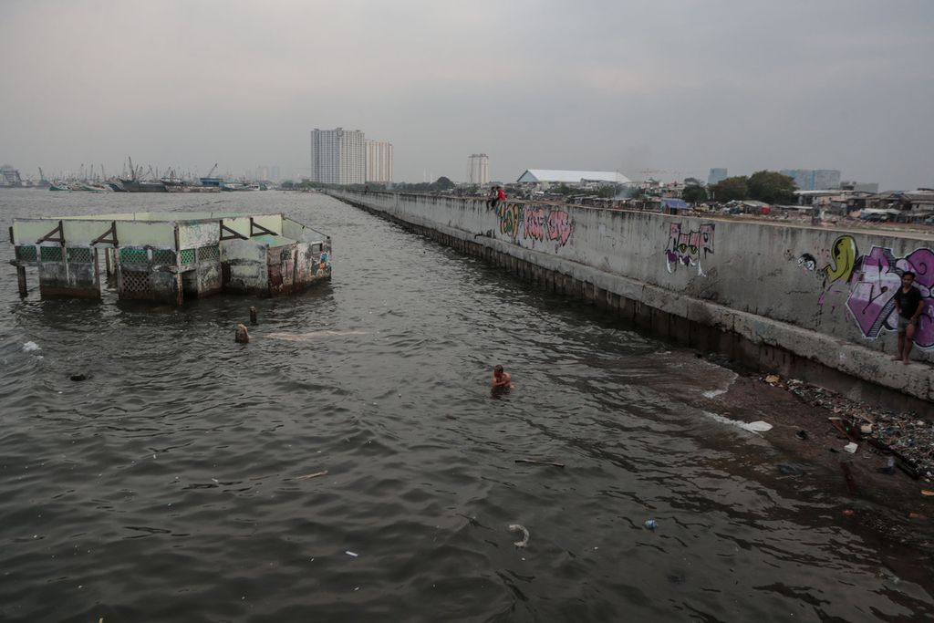 Warga berenang di balik tanggul laut raksasa di Muara Baru, Jakarta Utara, Rabu (21/6/2023). Tanggul laut raksasa menjadi salah satu upaya pemerintah untuk meredam banjir rob yang kerap terjadi di Jakarta Utara. 