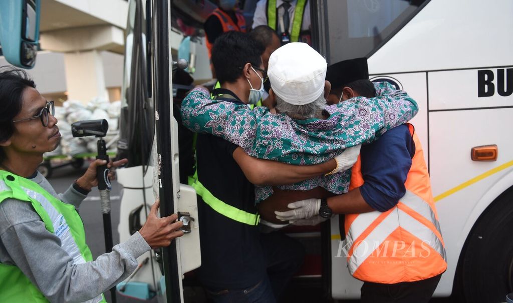  Jemaah haji kloter 1 asal Kabupaten Bangkalan yang kesulitan berjalan dibantu petugas menaiki bus setelah tiba di Bandara Juanda Surabaya, Sidoarjo, Jawa Timur, Selasa (4/7/2023).