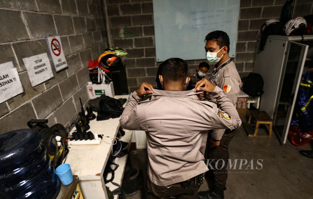 Petugas satpam yang akan bertugas bersiap sebelum menggantikan tugas jaga rekannya di sebuah pusat perbelanjaan ritel perabotan rumah di kawasan Kunciran, Kota Tangerang, Banten, Jumat (25/2/2022).