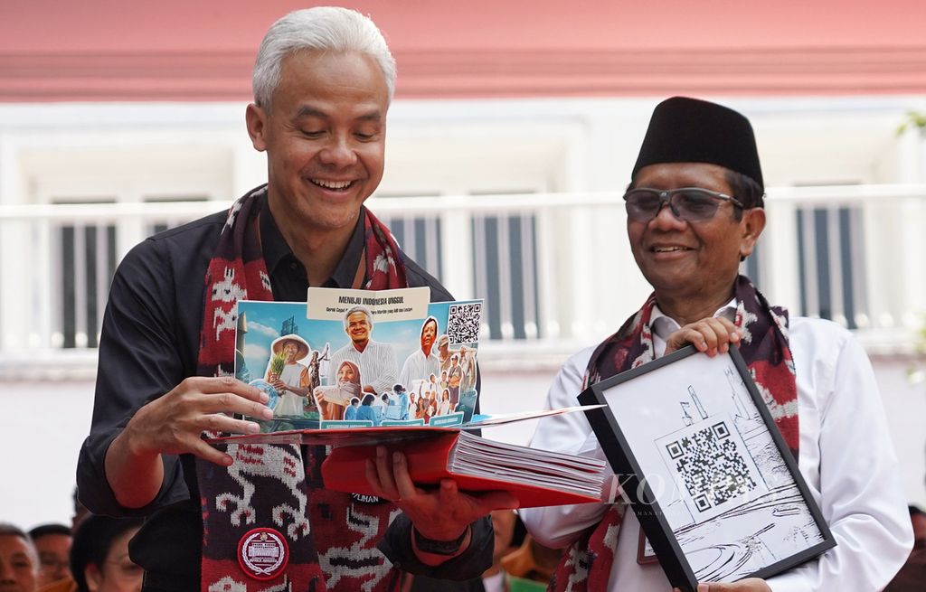 Pasangan bakal calon presiden dan calon wakil presiden Ganjar Pranowo dan Mahfud MD menunjukkan buku visi dan misi berbentuk <i>pop-up </i>tiga dimensi saat tiba di kantor Komisi Pemilihan Umum, Jakarta, Kamis (19/10/2023). 