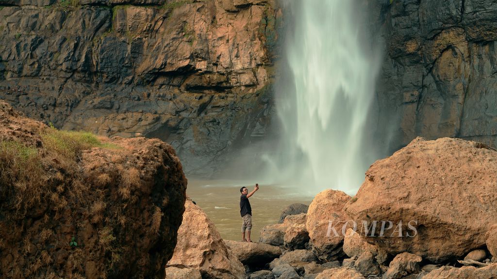  A tourist takes a photo with a 60-meter-high Cimarinjung waterfall in the Ciletuh-Palabuhanratu Geopark area in Ciwaru Village, Ciemas District, Sukabumi Regency, West Java, Thursday (4/8/2022).